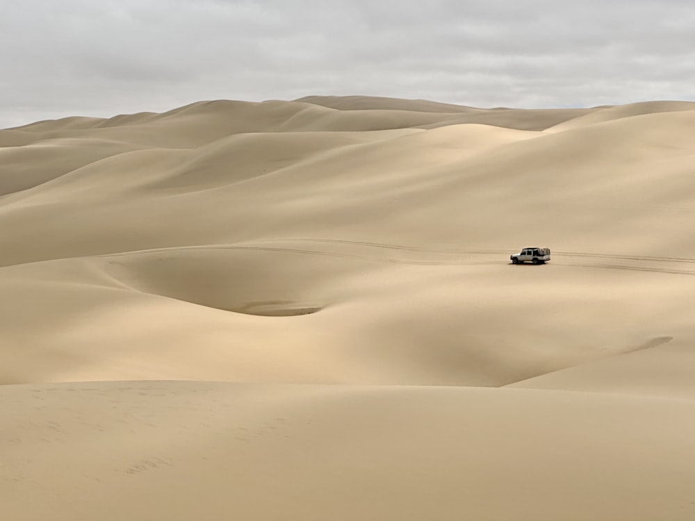 a jeep driving through the desert with sand dunes in the background