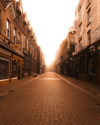 A cozy street scene of The Coombe in Dublin with vintage shopfronts and cobblestones bathed in soft afternoon light.