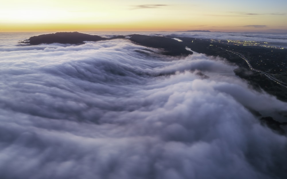 an aerial view of a mountain covered in clouds