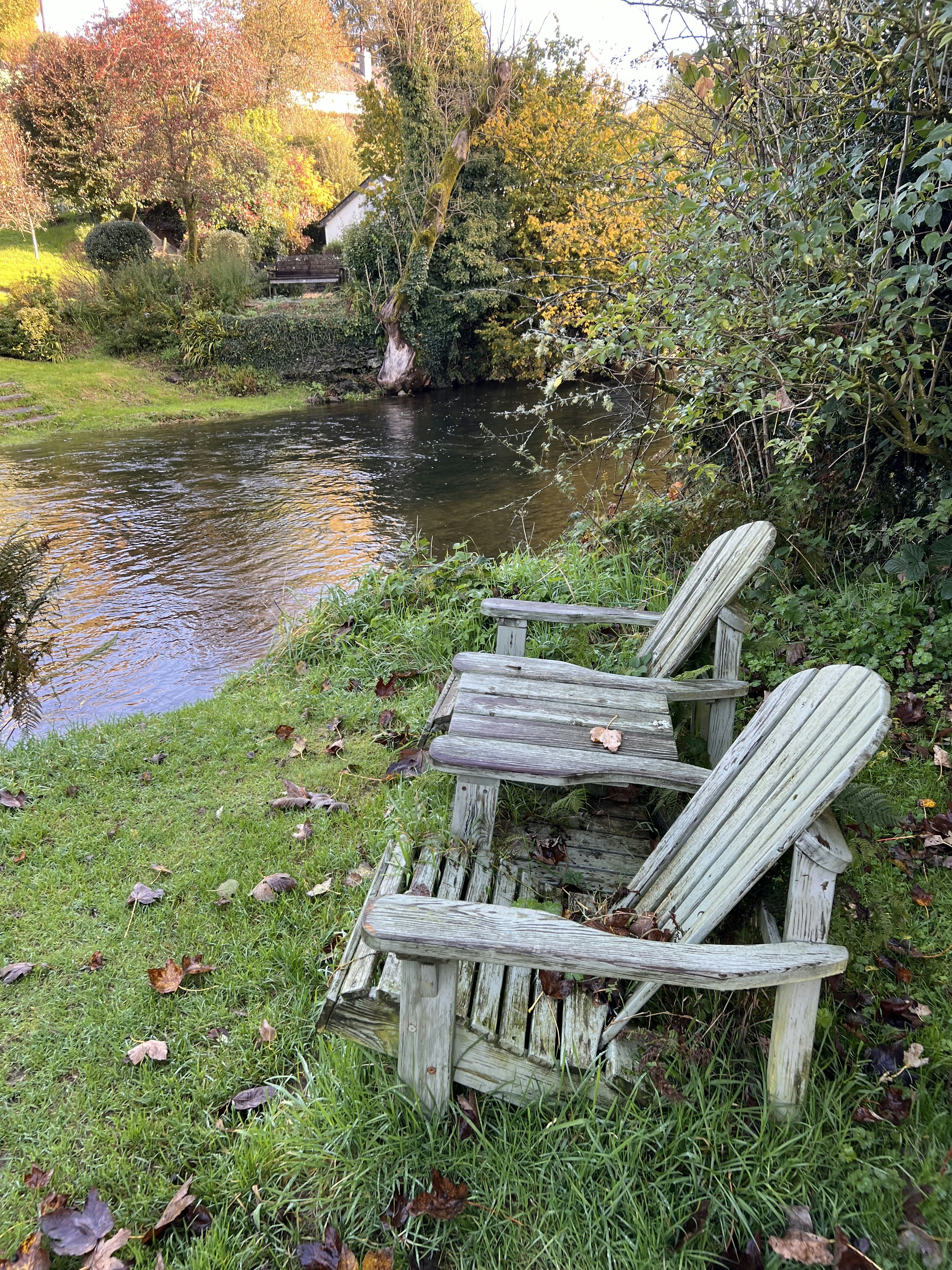 a couple of wooden chairs sitting next to a river
