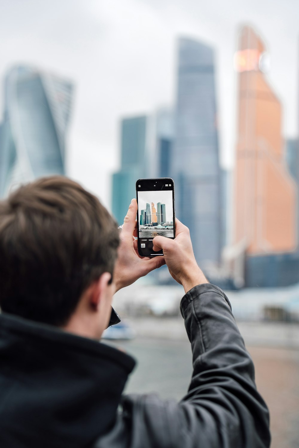 a man taking a picture of a city with his cell phone