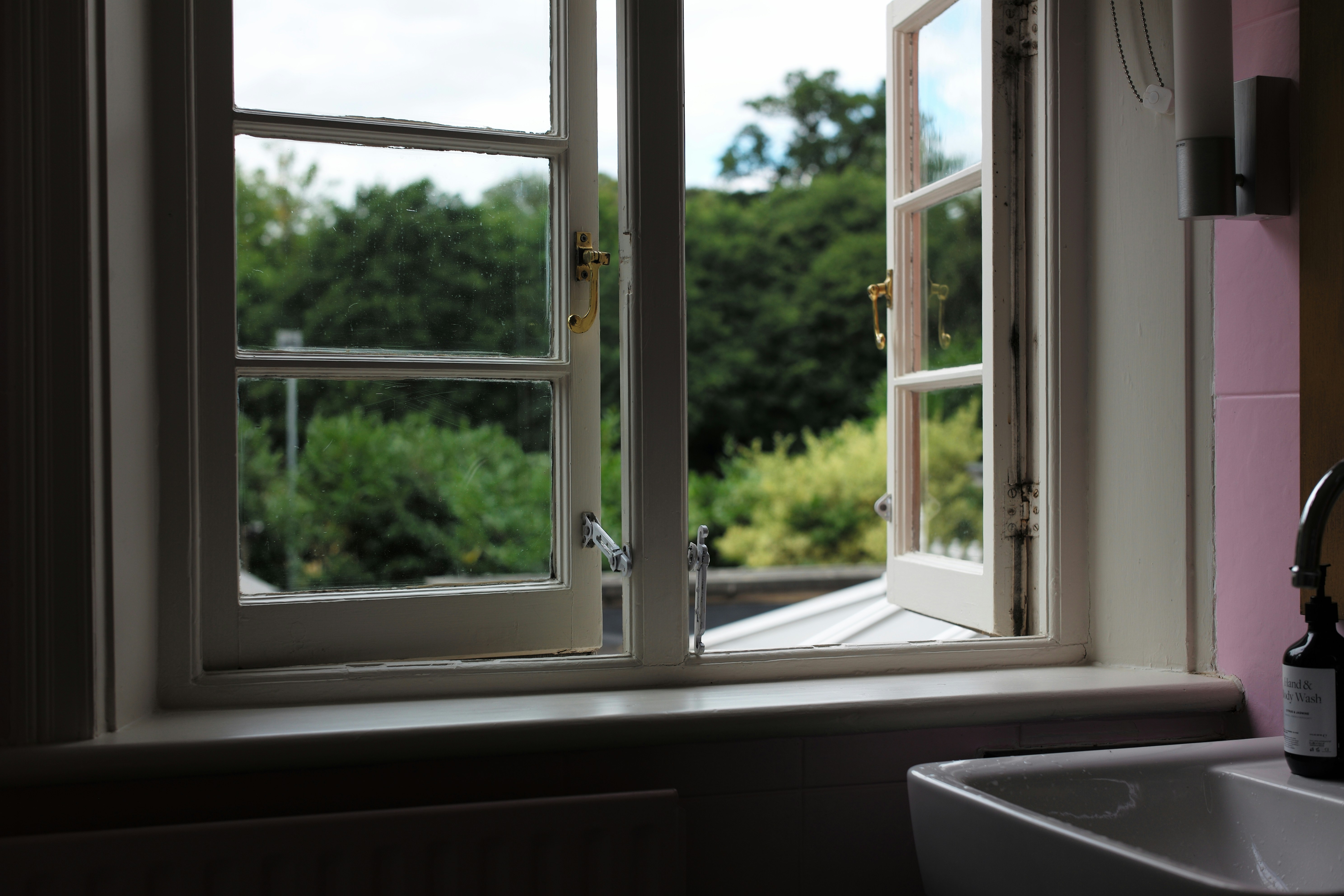 a bottle of wine sitting on a window sill next to a sink
