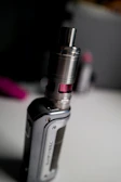 Close-up of a sleek electronic cigarette with vapor swirling around in a dark, moody setting