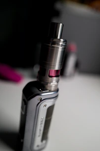 Close-up of a sleek, glowing vape device with neon purple accents on a dark reflective surface.