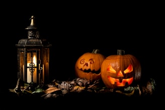 two carved pumpkins sitting next to a lantern