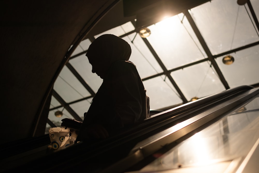 a silhouette of a person riding an escalator