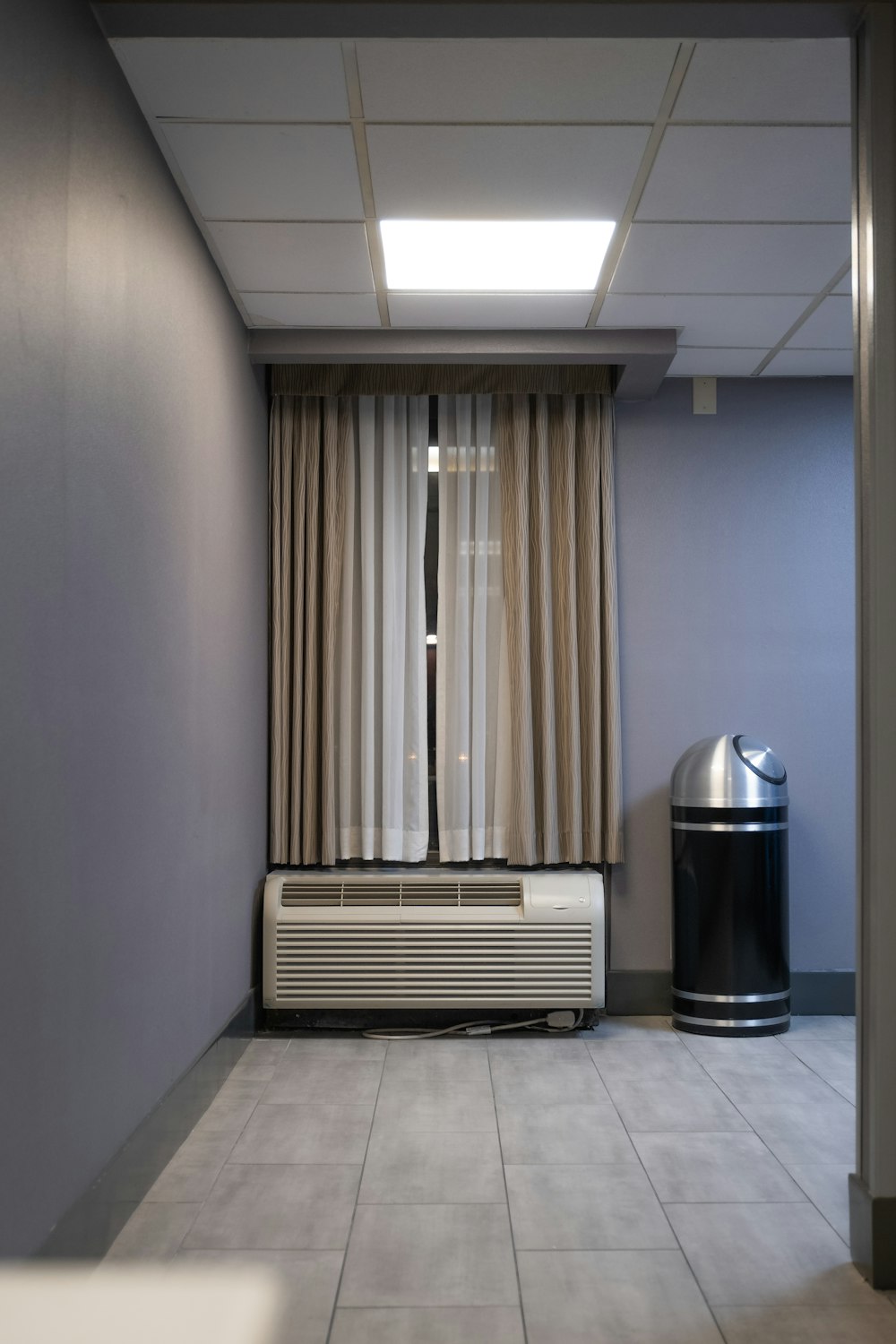a room with a heater and a trash can
