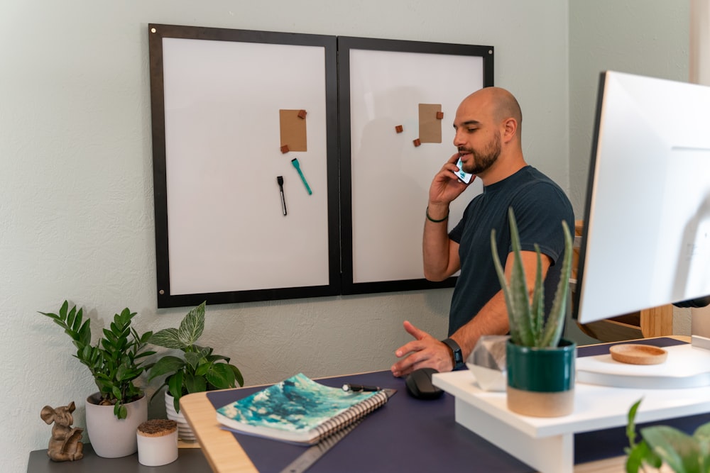 a man talking on a cell phone in front of a cake