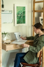 a woman sitting at a desk writing on a piece of paper