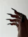 Close-up of a hand with deep black and metallic silver press-on nails glowing softly under low, cinematic lighting.