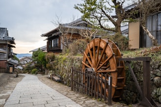 a wooden water wheel sitting on the side of a road