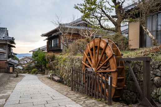 a wooden water wheel sitting on the side of a road