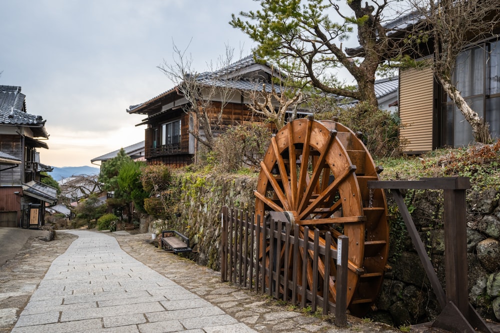 a wooden water wheel sitting on the side of a road