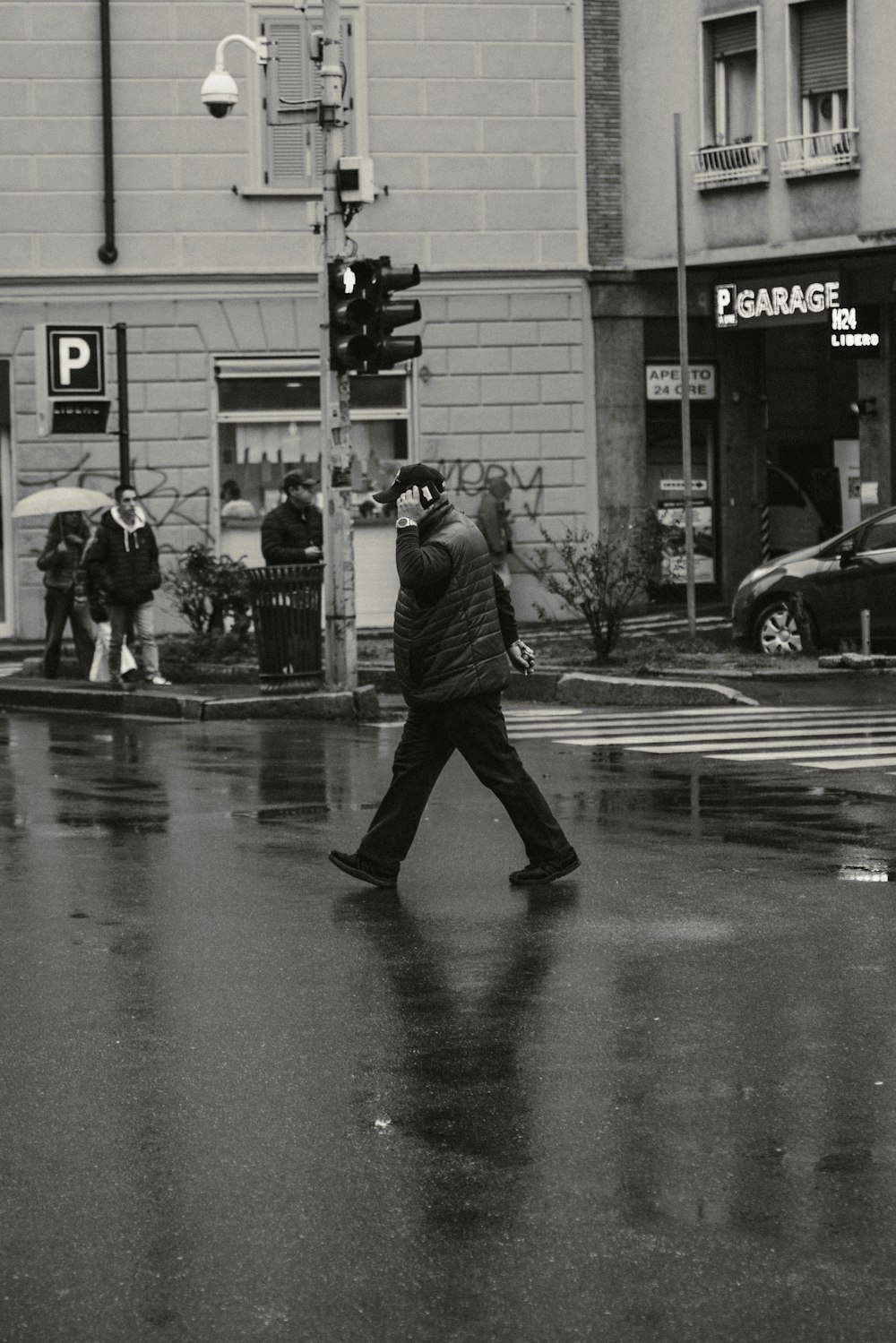a man walking across a street holding an umbrella