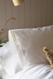a teddy bear sitting on top of a bed next to pillows