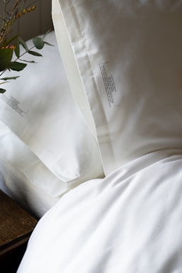 a close up of a bed with white sheets and pillows