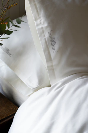 A knee pillow placed between legs on a white sheet, highlighting its contour.