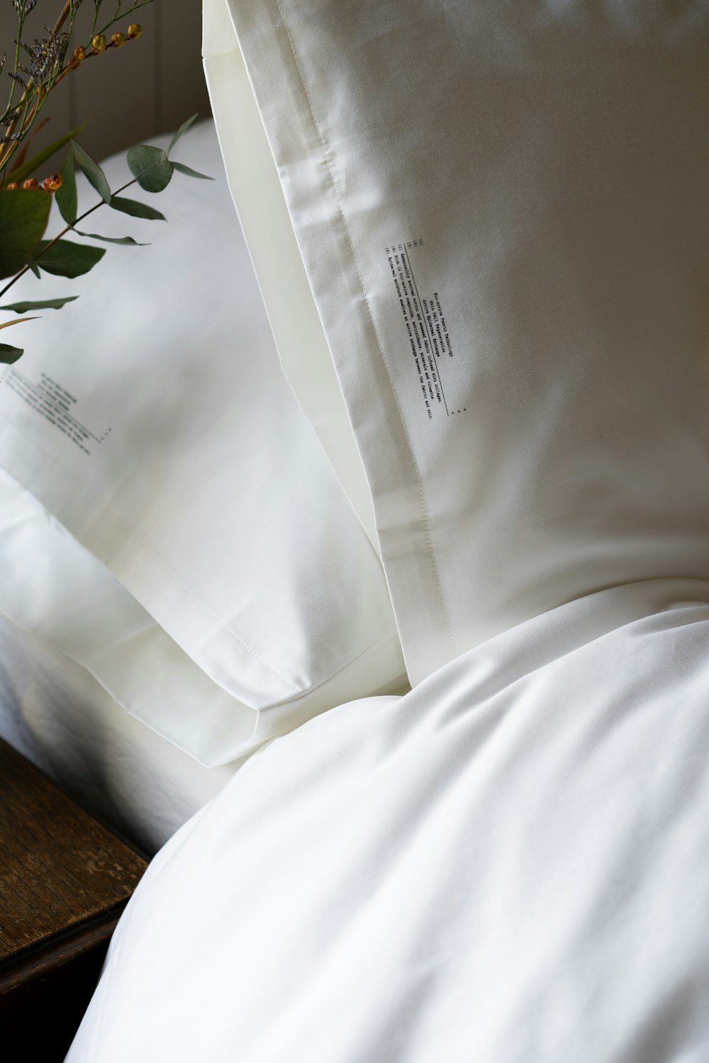 a close up of a bed with white sheets and pillows