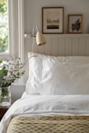 a bed with a white comforter and pillows