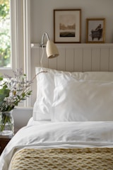 a bed with a white comforter and pillows