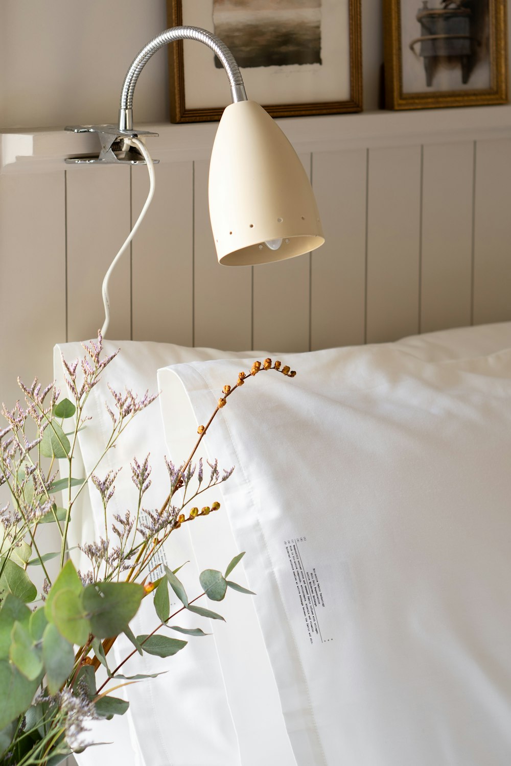 a bed with a white comforter and a white lamp