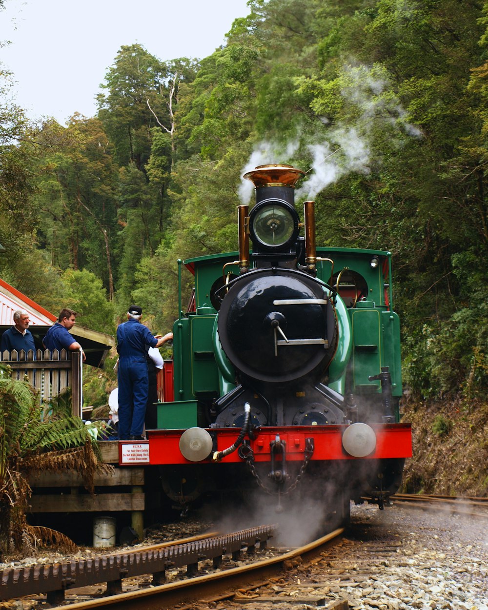 Un tren verde y rojo viajando por las vías del tren