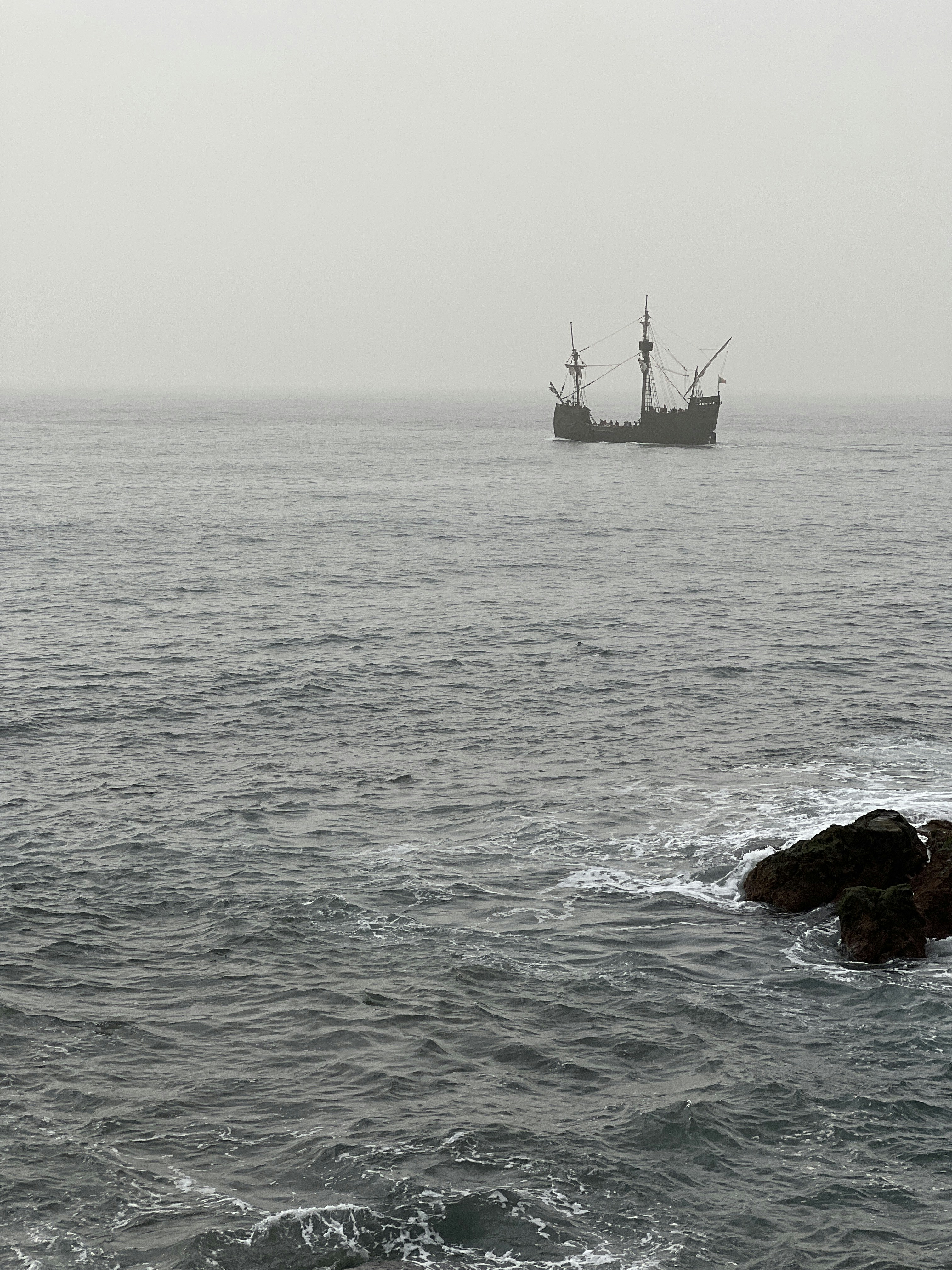 A ship in the ocean with rocks in the foreground photo – Free Portugal ...
