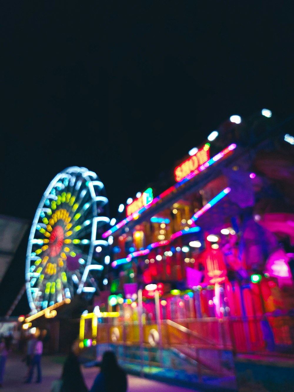 a carnival with a ferris wheel lit up at night