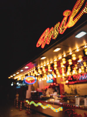 A lively vendor booth decorated with pixel art banners and glowing arcade signs.