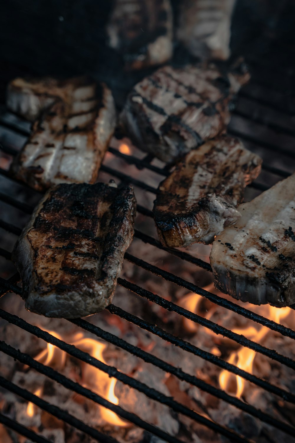 steaks cooking on a grill with flames in the background