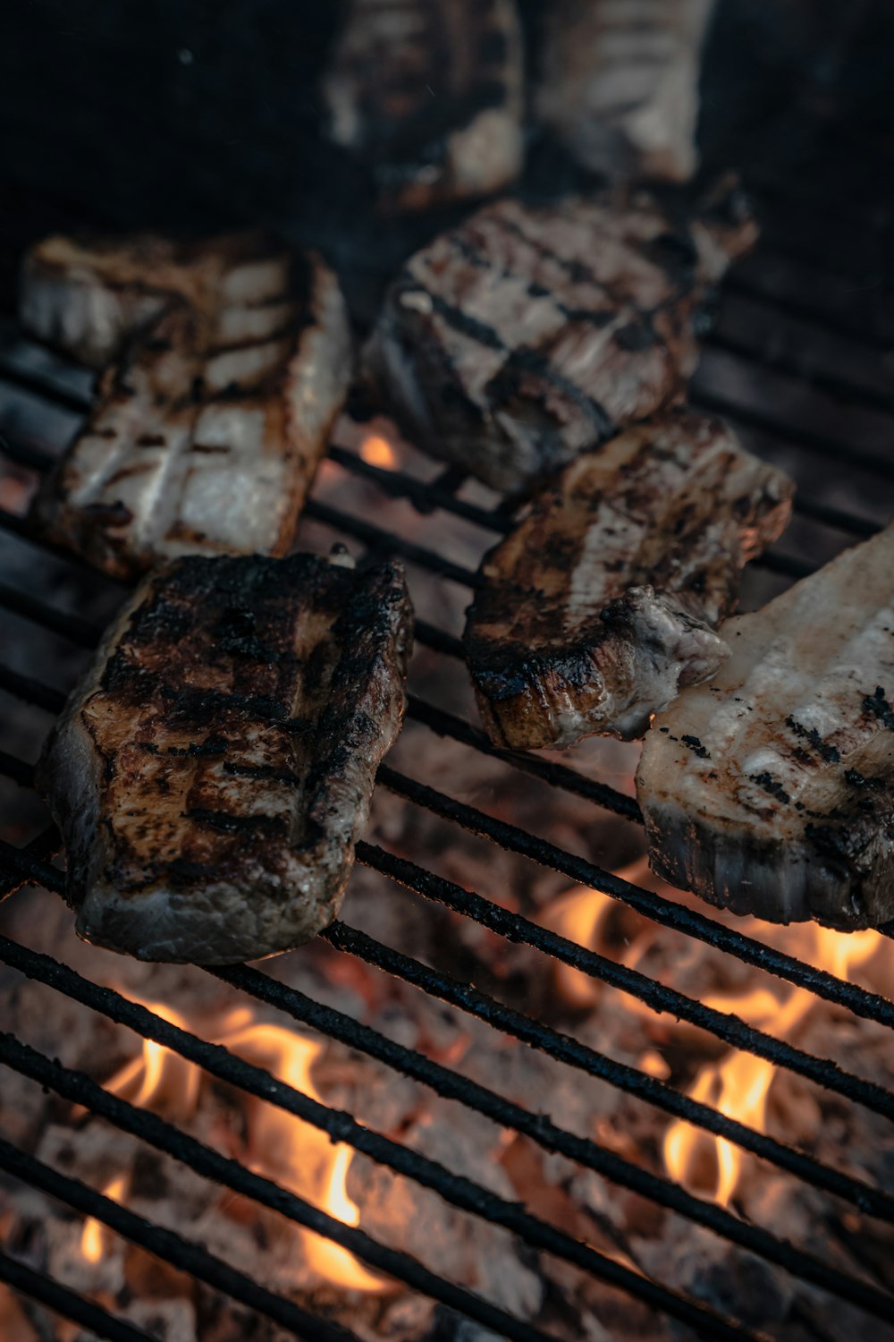 steaks cuisant sur un gril avec des flammes en arrière-plan