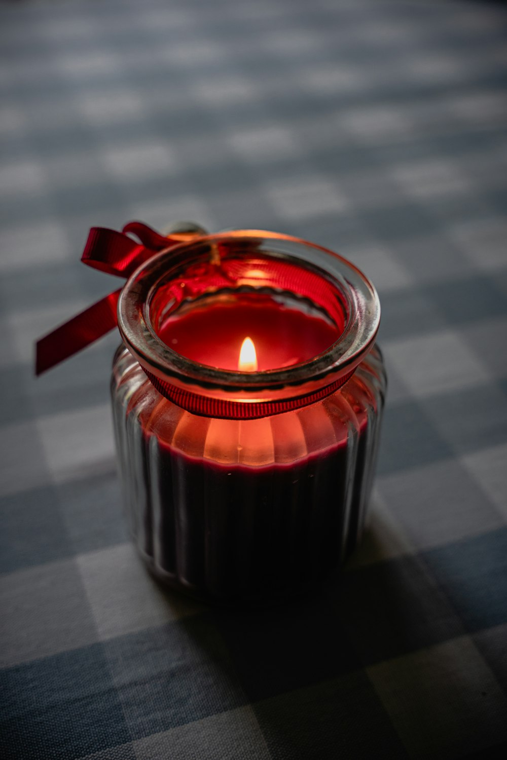 a lit candle sitting on top of a checkered table cloth
