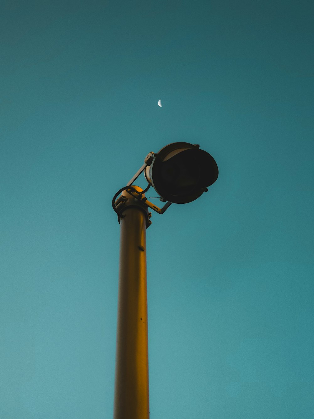 a street light with a half moon in the sky