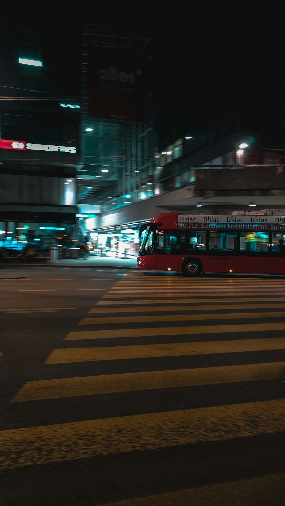 a red bus driving down a street at night