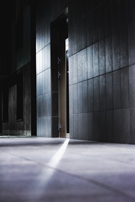 A dimly lit hotel corridor with a broken CCTV camera visible on the ceiling.