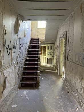 An open, dimly lit hallway with peeling wallpaper symbolizing secrets behind the walls.