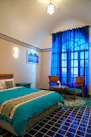 a bed room with a neatly made bed and blue curtains