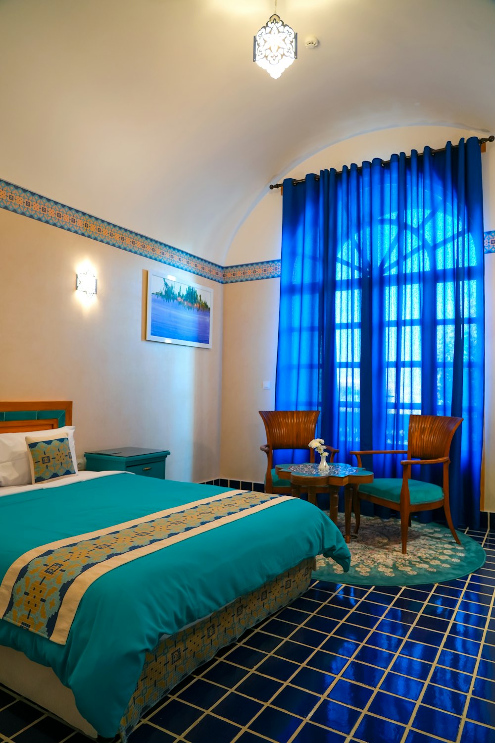 a bed room with a neatly made bed and blue curtains