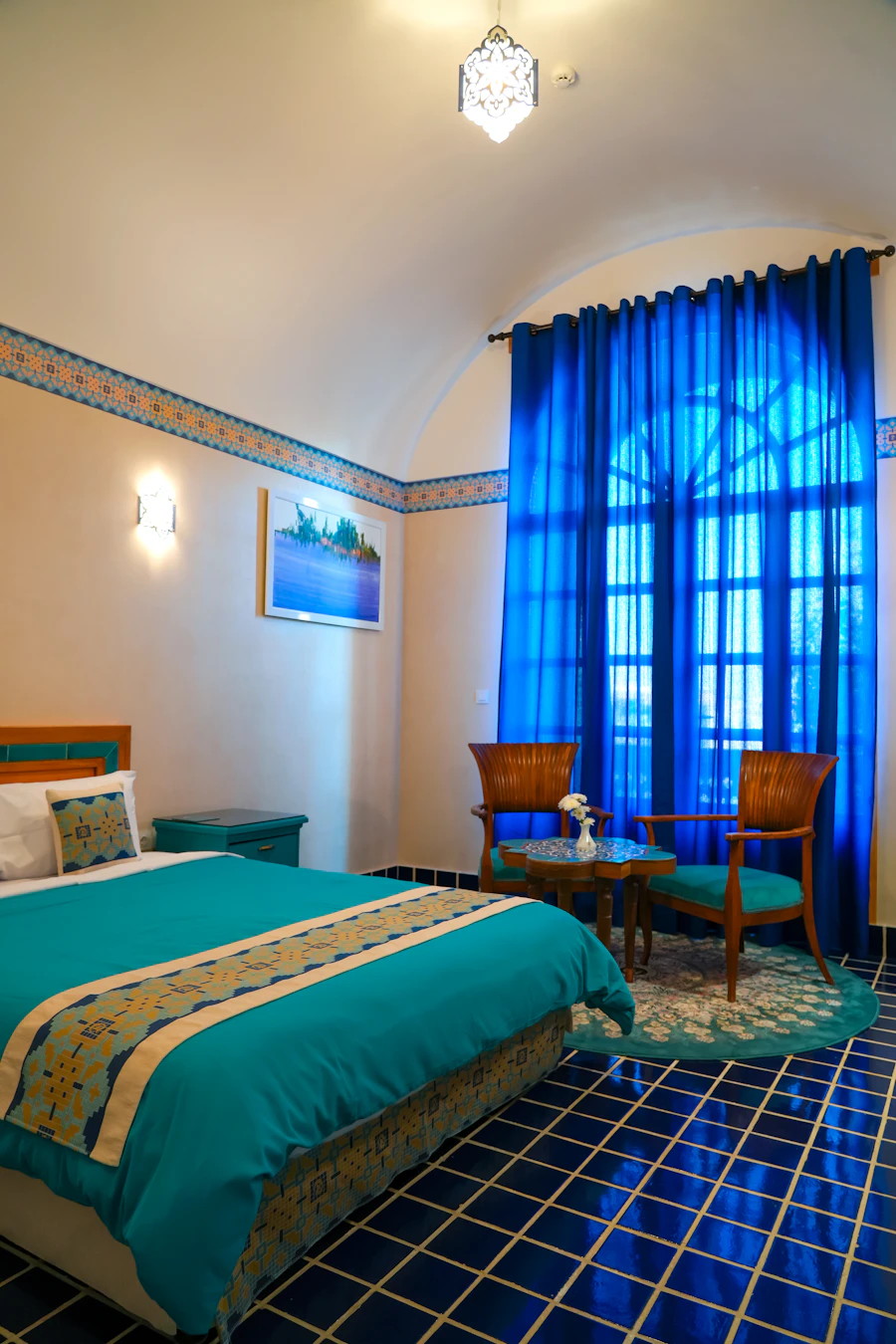 Chambre Soukaina — lit fait avec rideaux bleu profond