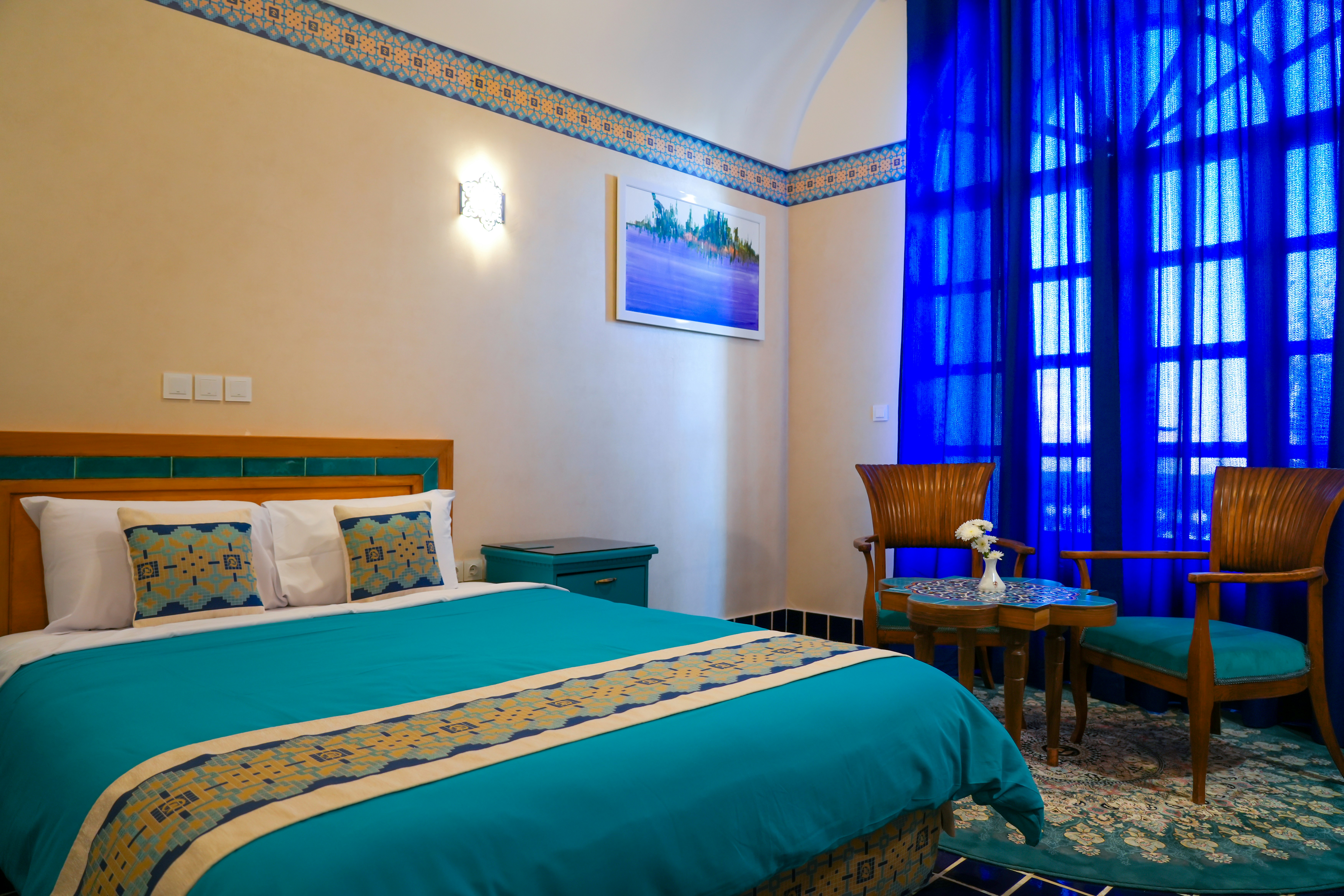 a bedroom with a bed, chair, and a painting on the wall