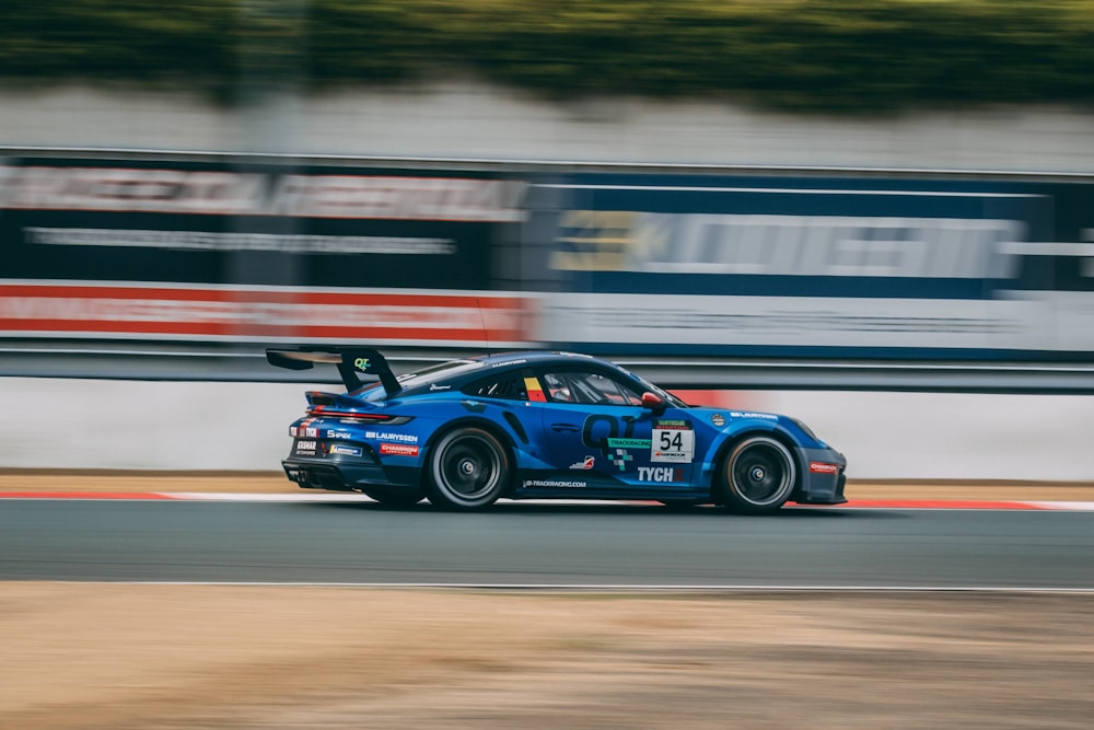 a blue race car driving down a race track