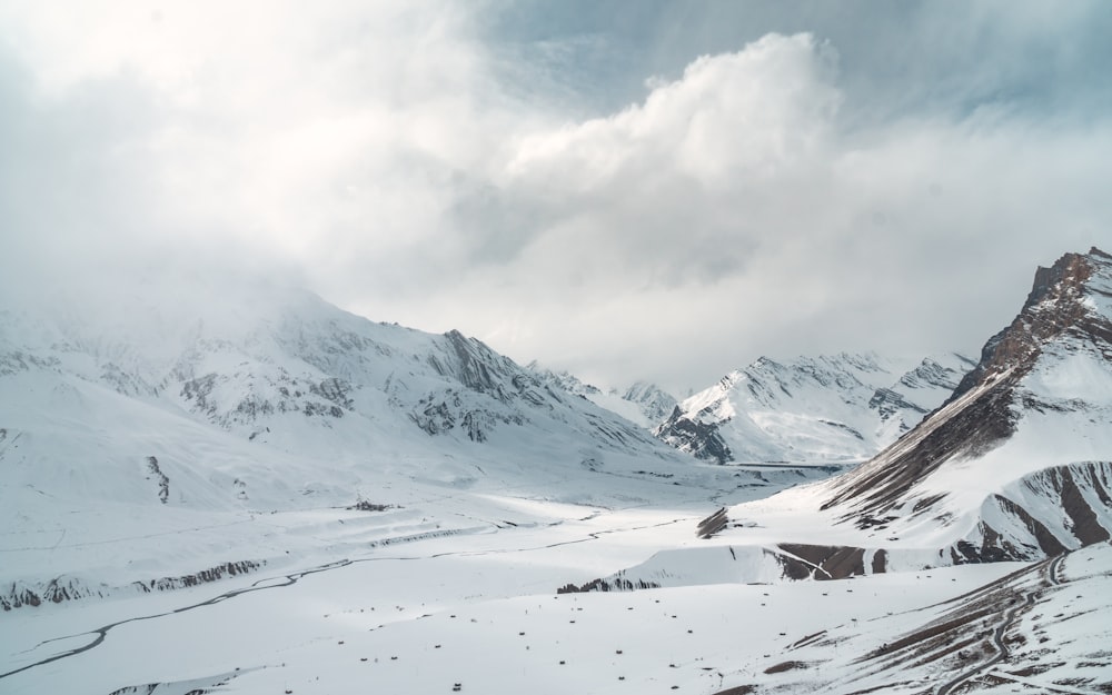 a snow covered mountain range under a cloudy sky