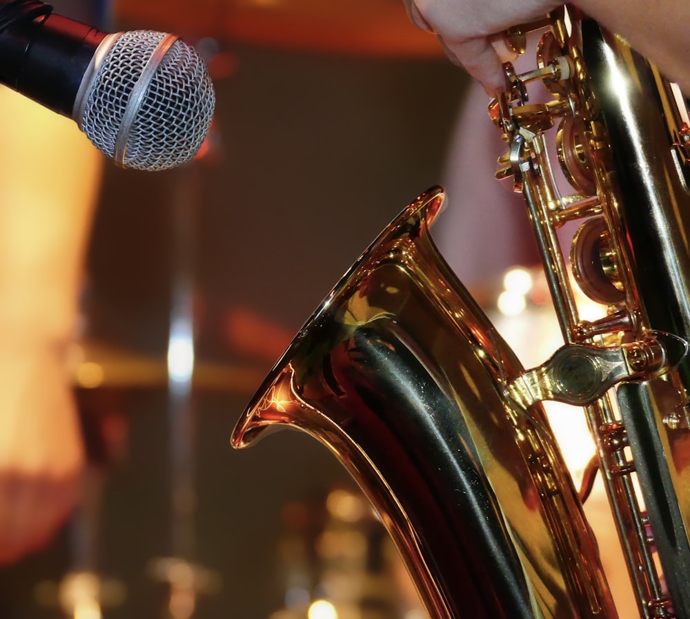 a close up of a person holding a saxophone in front of a microphone