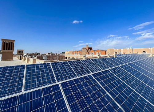 A rooftop solar panel installation under a clear blue sky in Baghdad.
