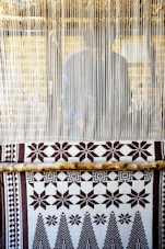 Intricate handwoven Tripuri handloom fabric displayed on a traditional wooden loom.