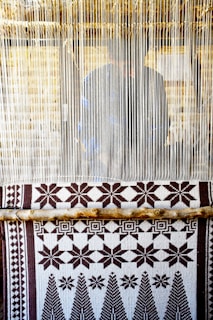 Handwoven kente cloth displayed on a wooden loom in a bright artisan workshop