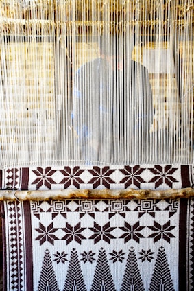 Handwoven kente cloth displayed on a wooden loom in a bright artisan workshop