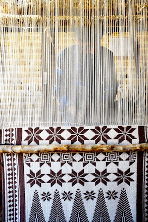Intricate handwoven Tripuri handloom fabric displayed on a traditional wooden loom.
