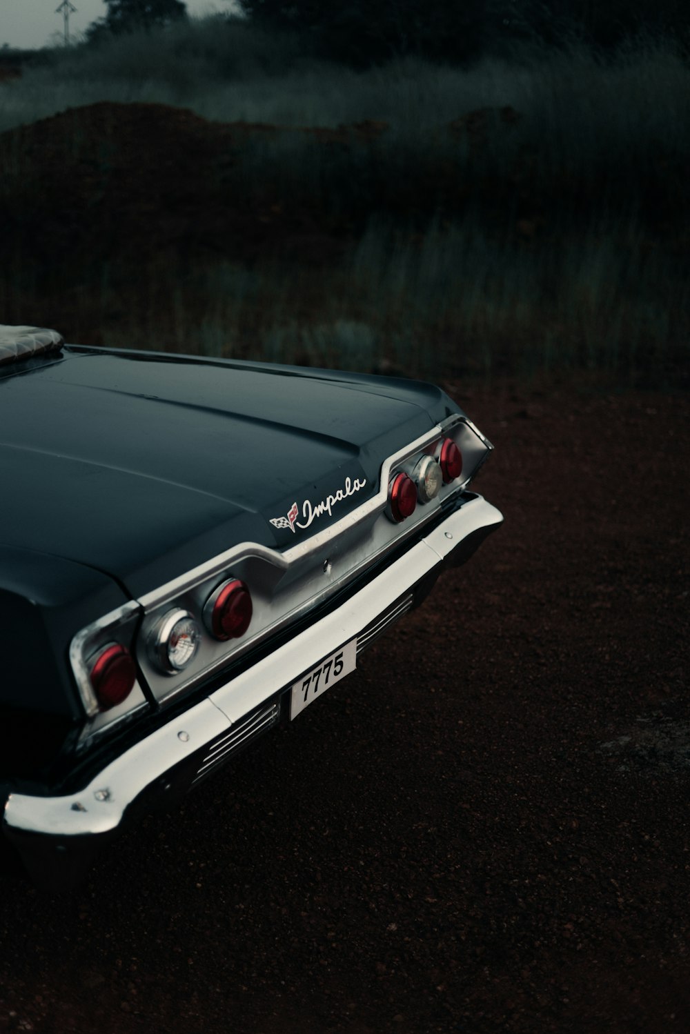 a black and white car parked on a dirt road