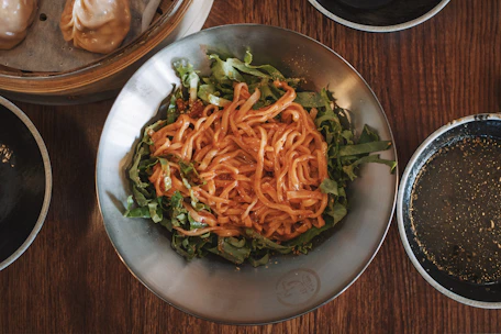 Elegant plating of a steaming bowl of Asian-inspired noodles with chopsticks.